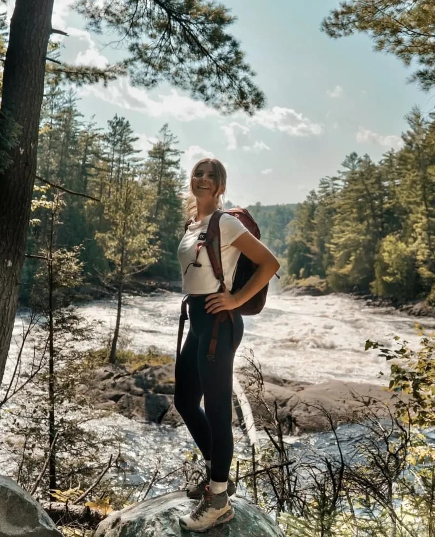 Creator with a backpack hiking beside a river